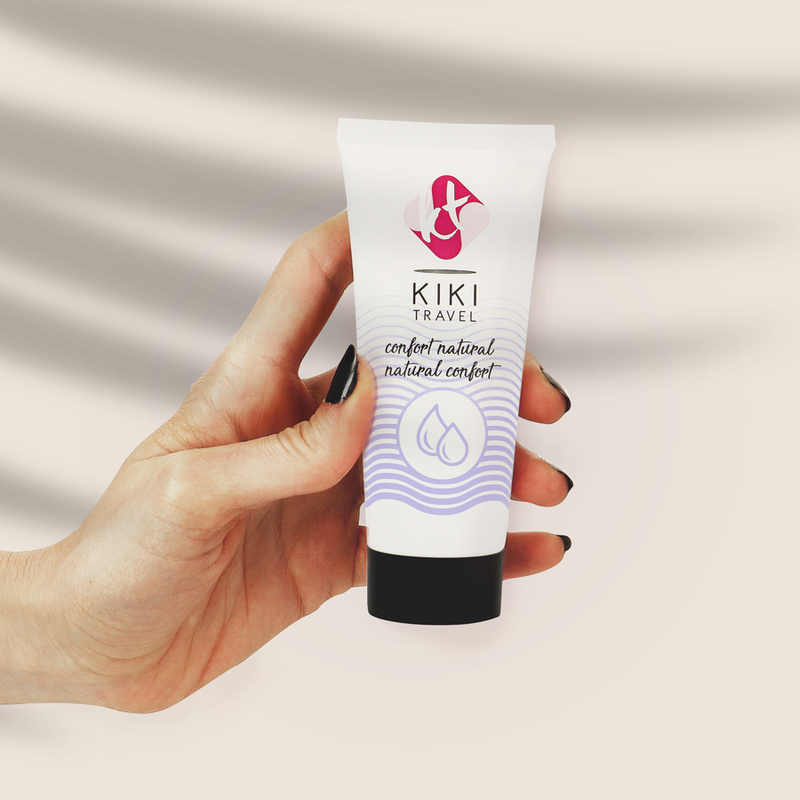 Hand holding a KIKI Travel product tube against a neutral background