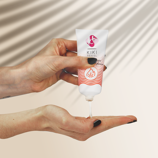 Hand holding a KIKI travel tube with a beige background