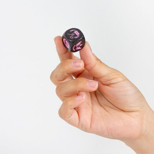 Hand holding a black and pink die against a light gray background