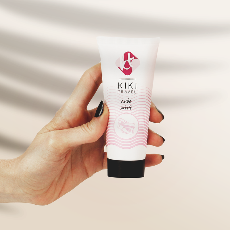 Hand holding a KIKI Travel tube against a neutral background