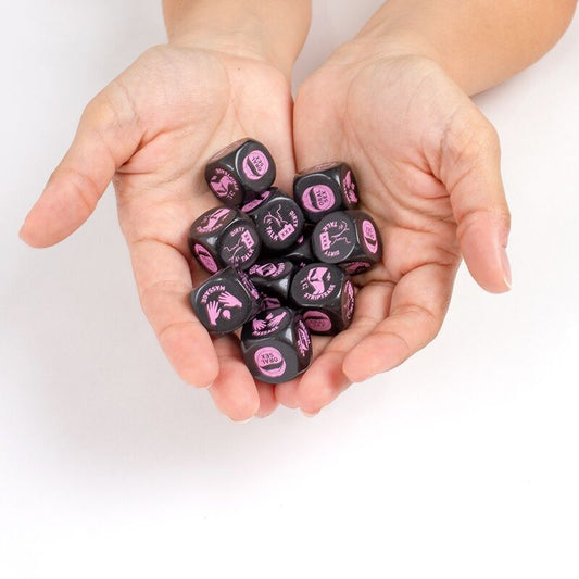 Hands holding black dice with pink text on a white background