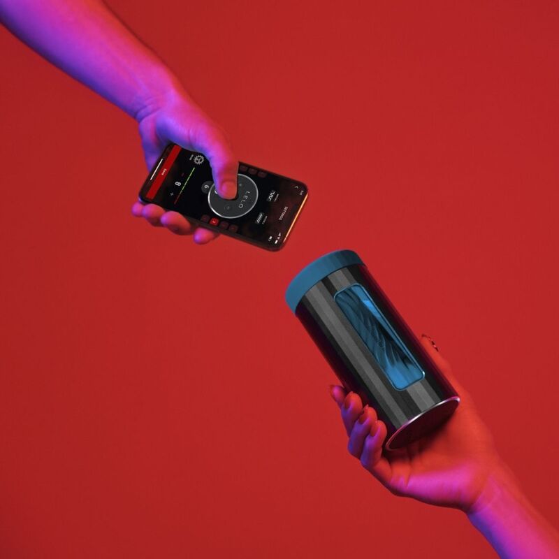 Person holding a smartphone with a music app and a cylindrical device on a red background